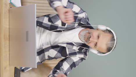 Vertical-video-of-Old-man-looking-at-laptop-is-happy-and-dancing.
